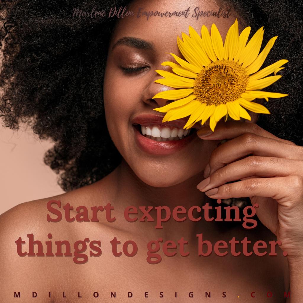 Beautiful Black woman with large curly afro smiling with her eyes closed, holding a yellow  flower before her left eye. Text states: Marlene Dillon Empowerment Specialist "Start expecting things to get better." mdillondesigns.com